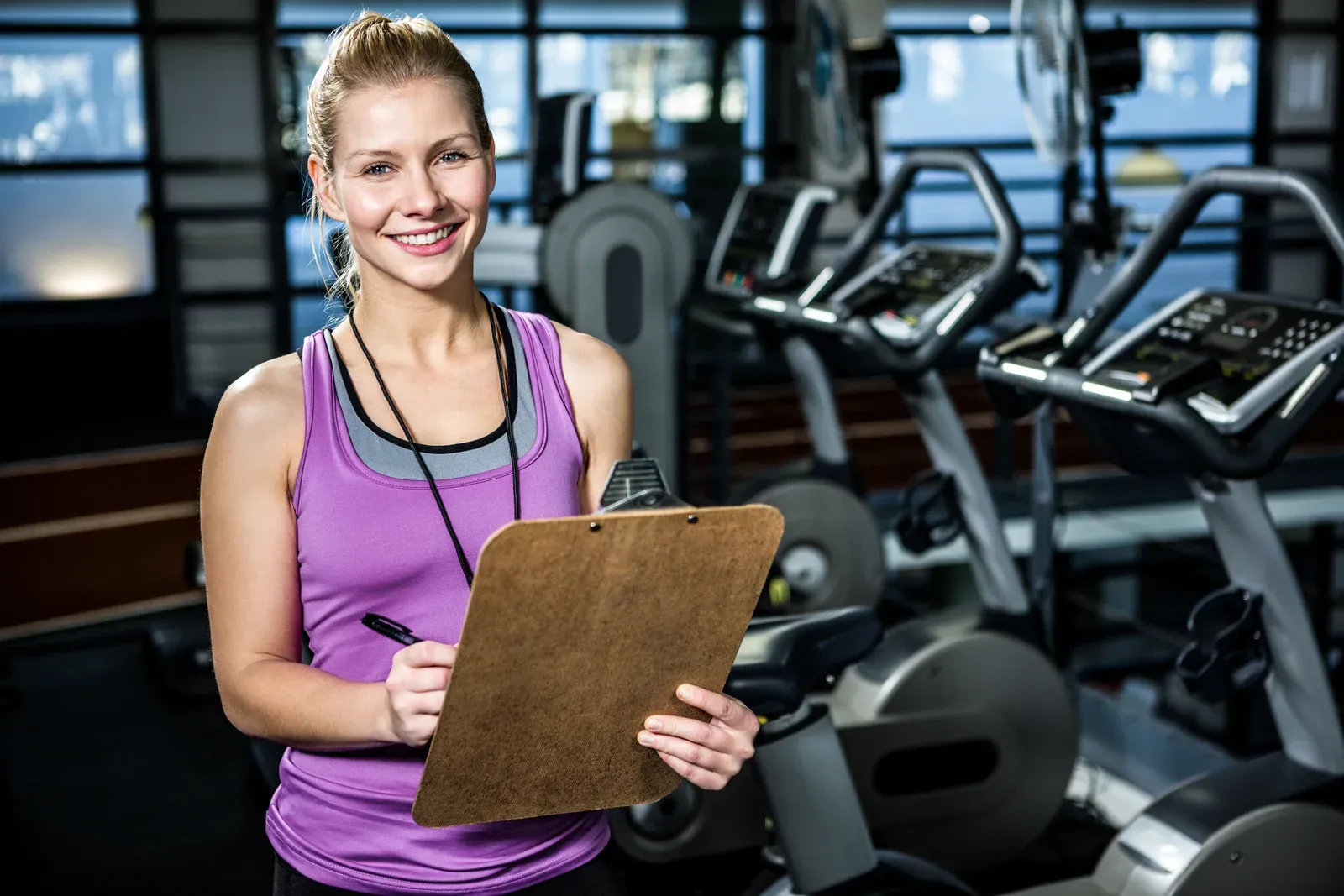 A trainer recording baseline fitness measurements on a clipboard beside a client