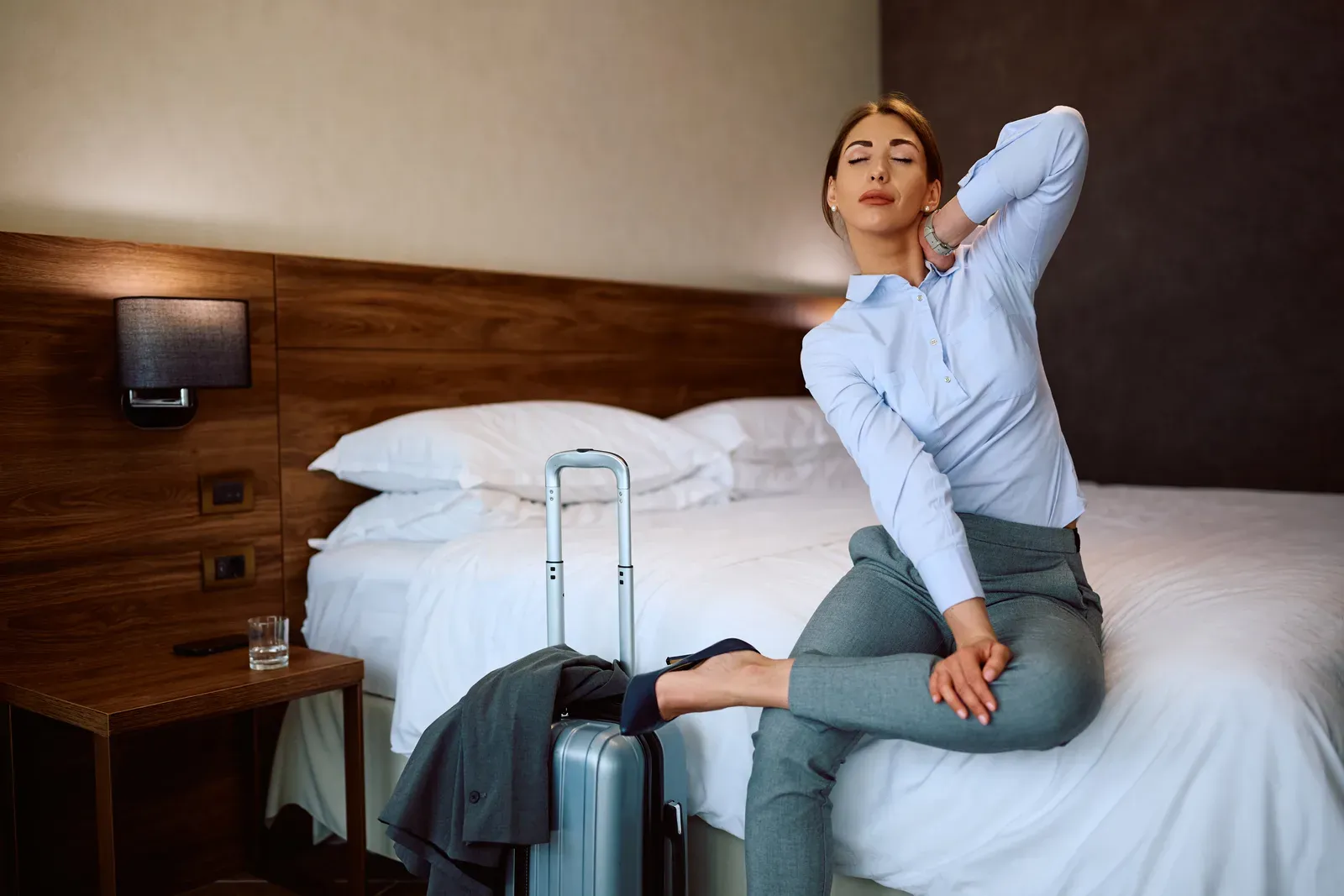 Exhausted businesswoman stretching on a hotel room bed, a way to unwind between rotations