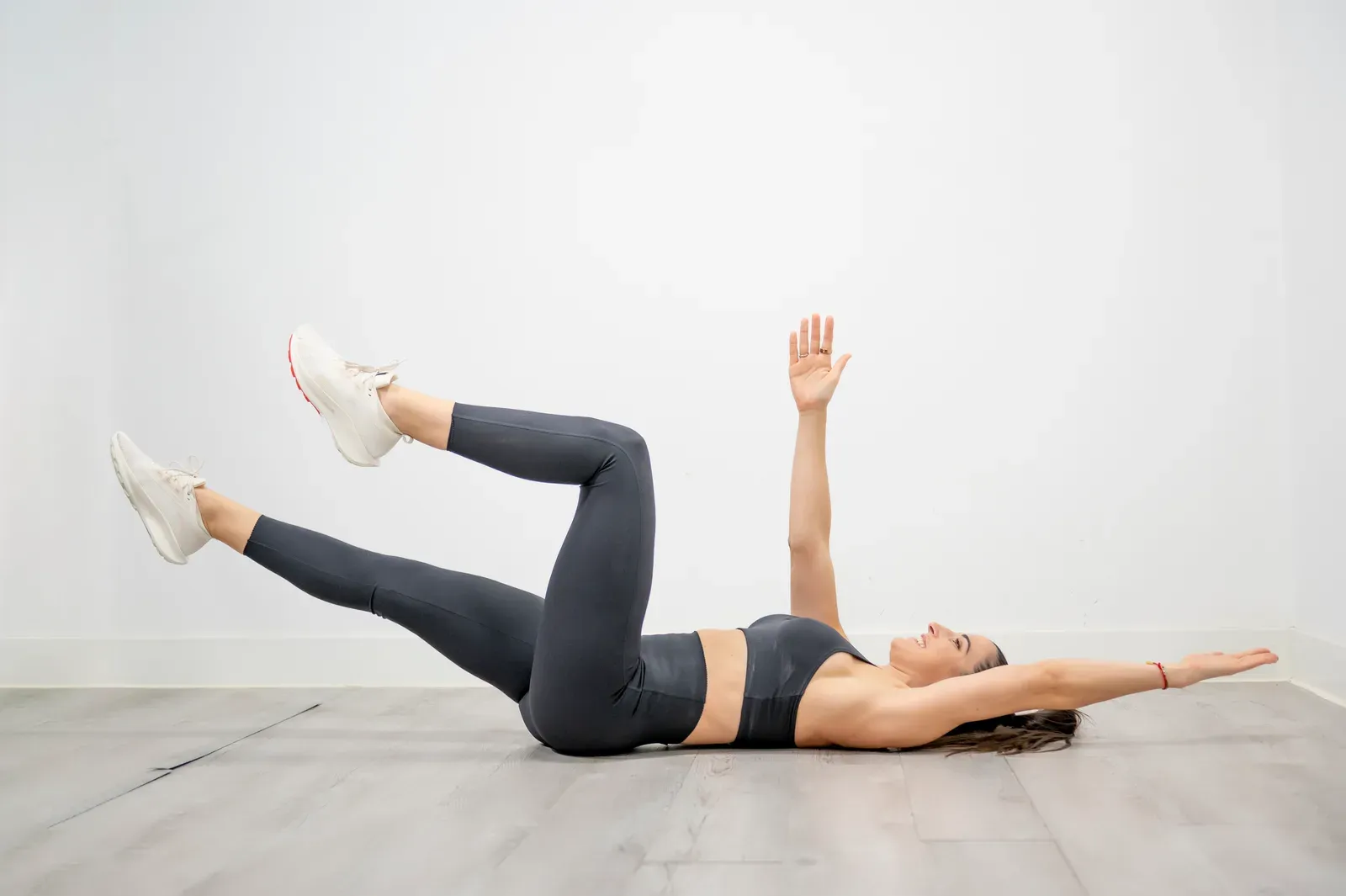 Woman performing a dead bug exercise, lowering the opposite arm and leg for core control and pelvic position