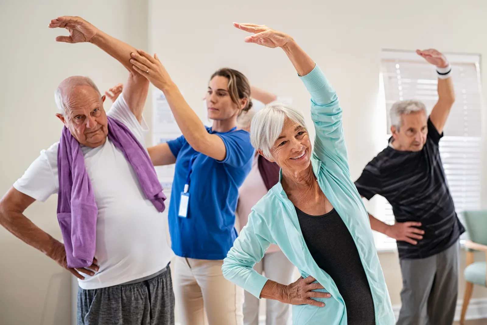Senior people stretching with a trainer at a retirement community, gentle work for hunched posture