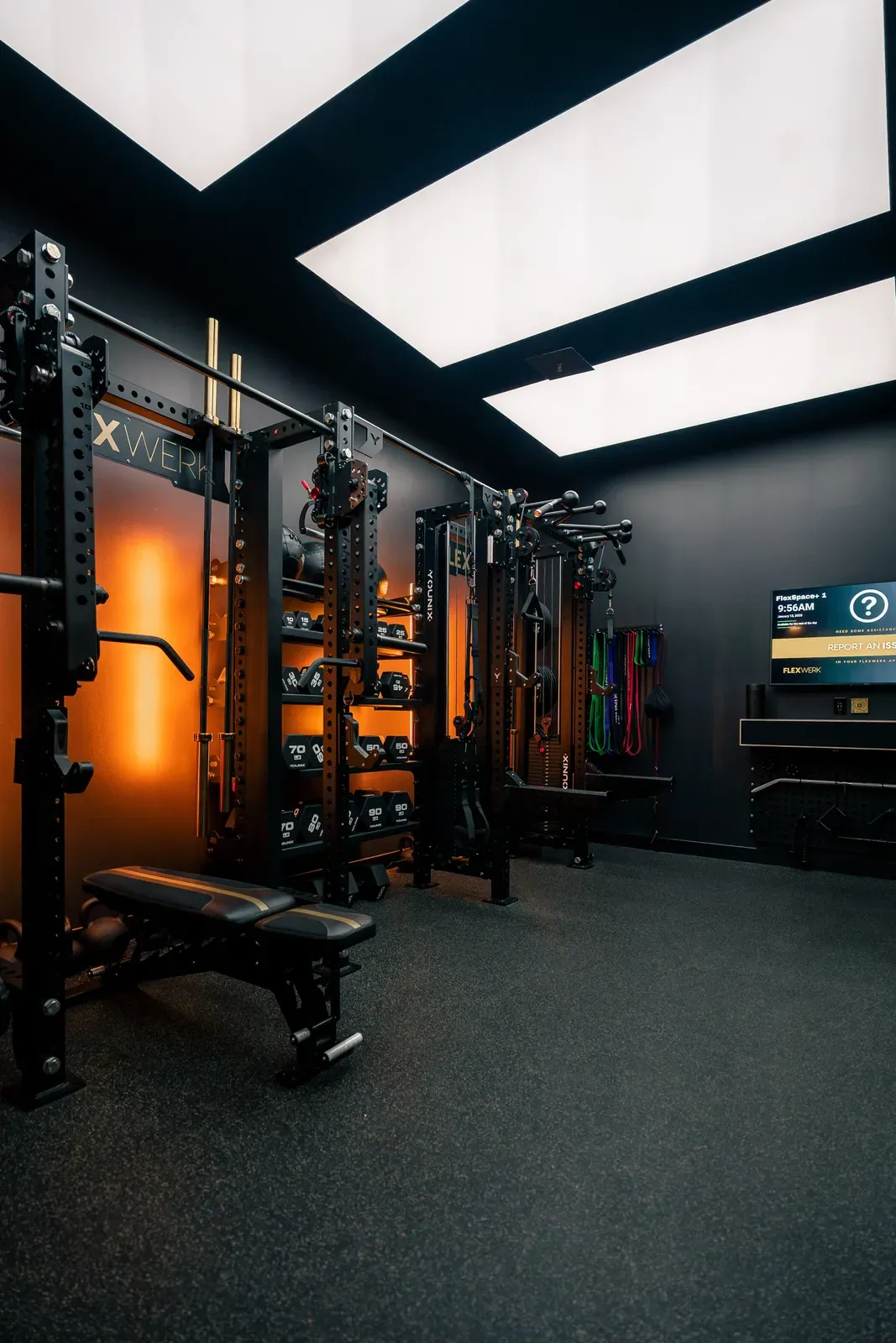Dumbbell racks, adjustable bench, and cable equipment inside a FlexSpace Plus room at FlexWerk Carmel
