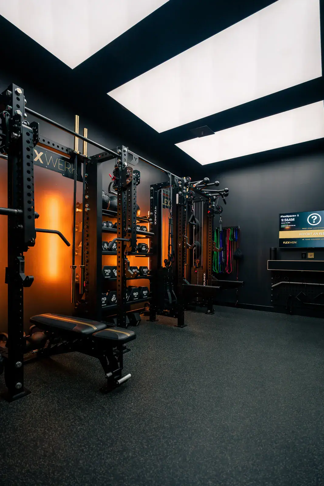 Dumbbell racks, adjustable bench, and cable equipment inside a FlexSpace Plus room at FlexWerk Carmel