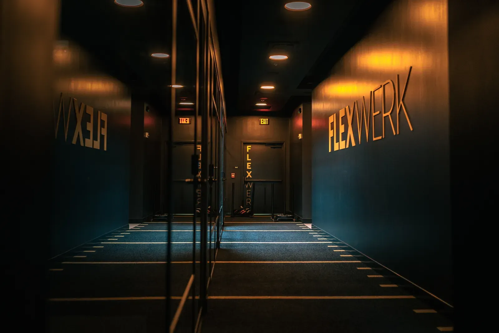 The turf corridor between private training spaces at FlexWerk Carmel, with sleds and FLEXWERK signage