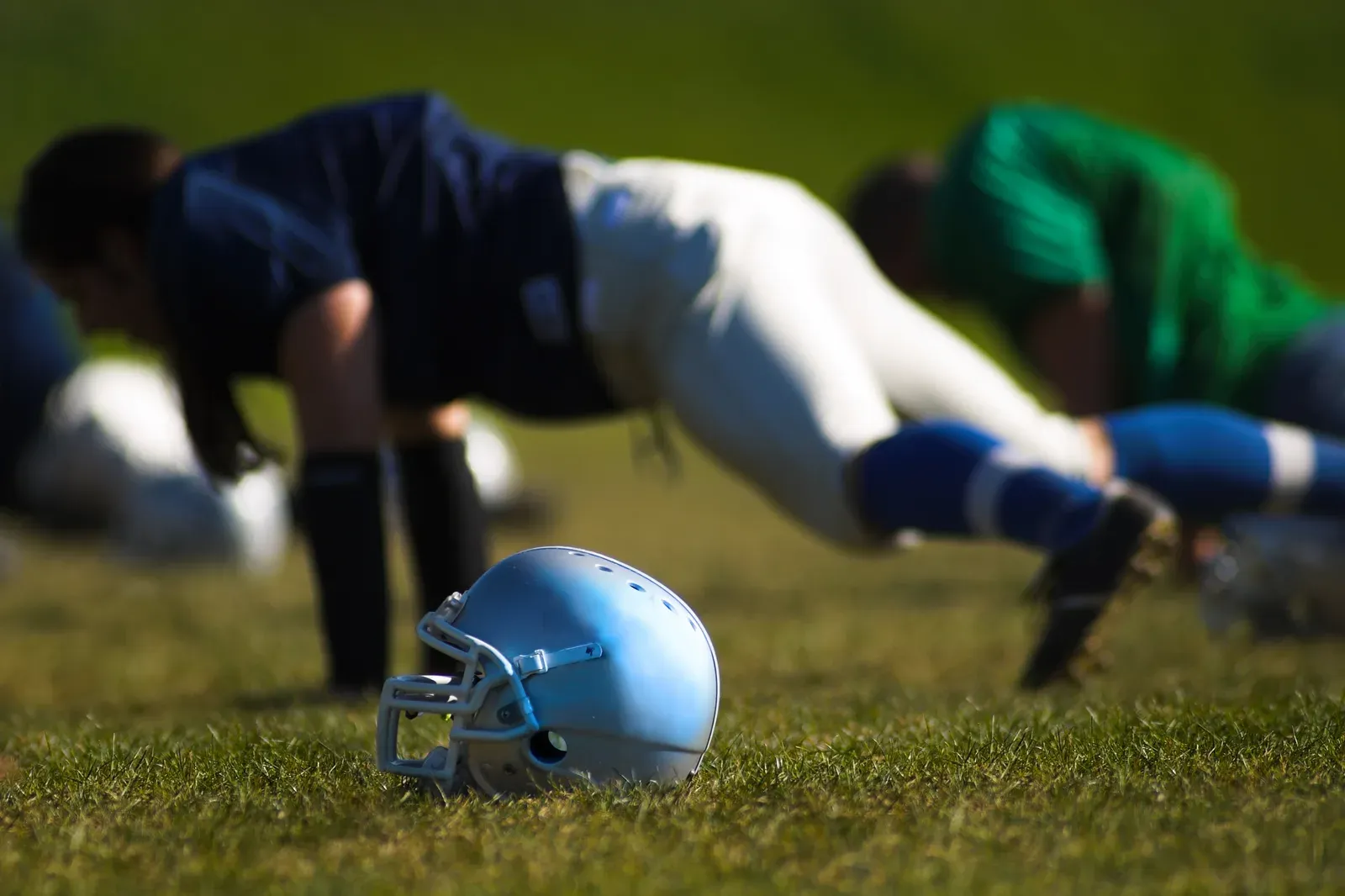 Football player driving a sled across a training field at sunset