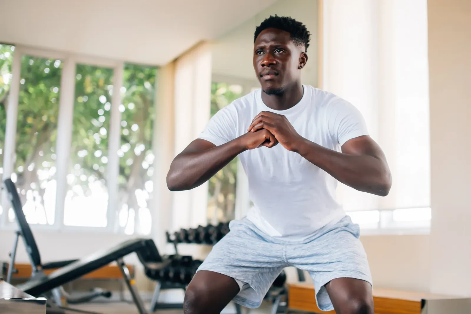 African American sportsman squatting in the gym, a core lift in a three-day full body routine