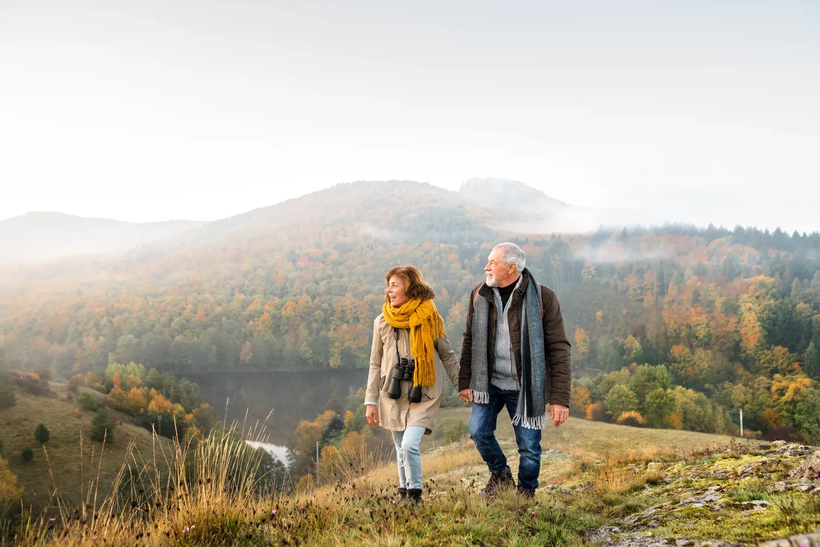 An older couple walking together on an autumn trail