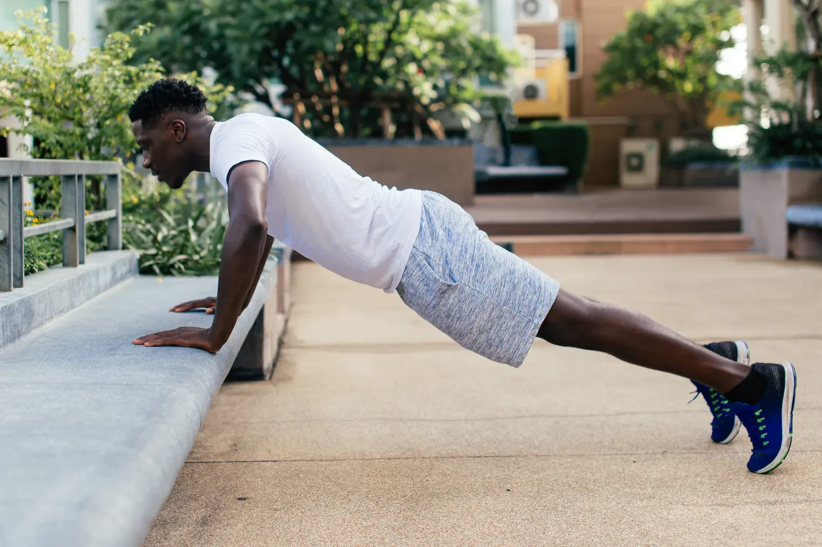 Young man doing a push-up in a city park, a bodyweight move for a summer plan before college