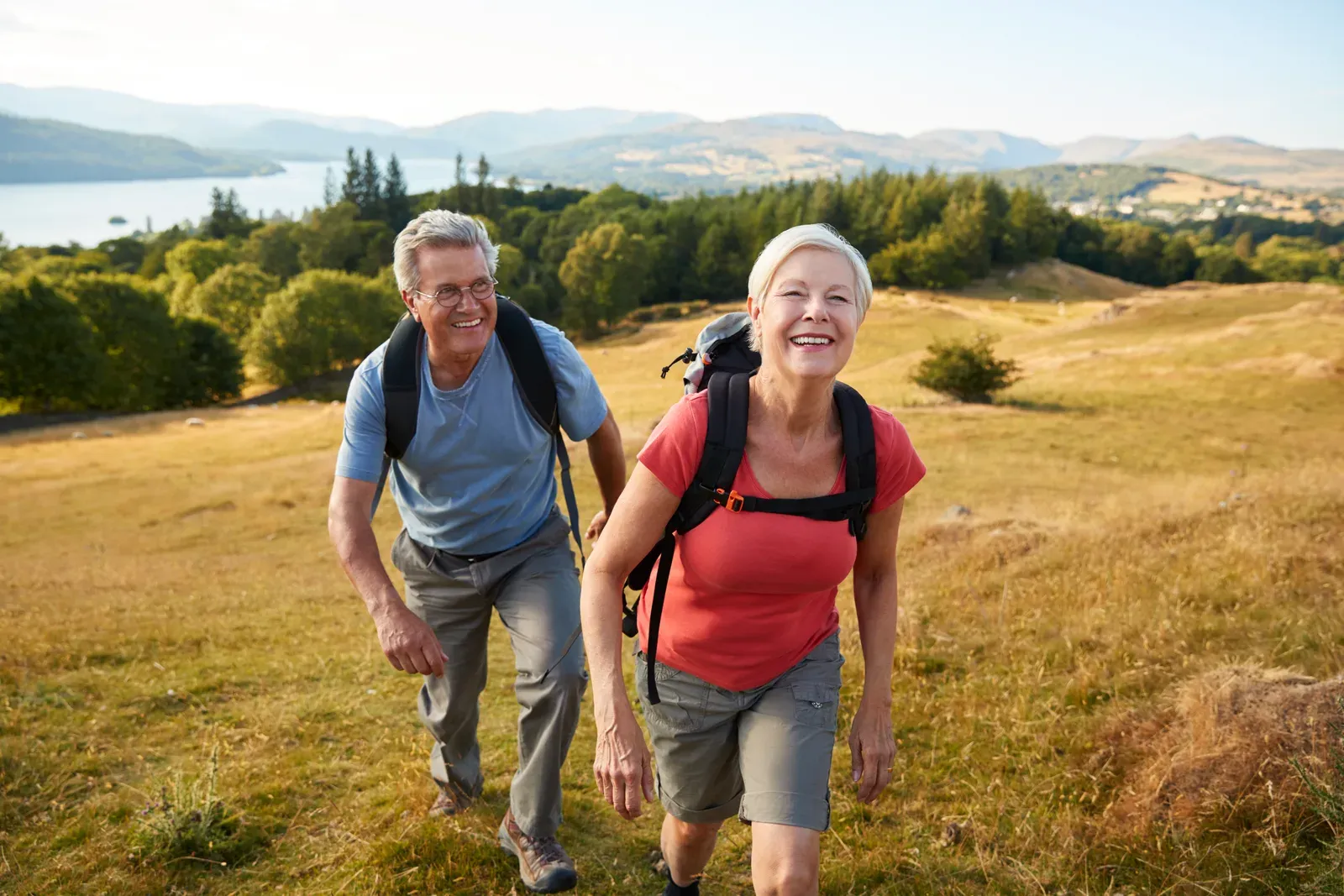 Senior couple climbing a hill on a hike through the countryside together, the goal of uphill hiking fitness