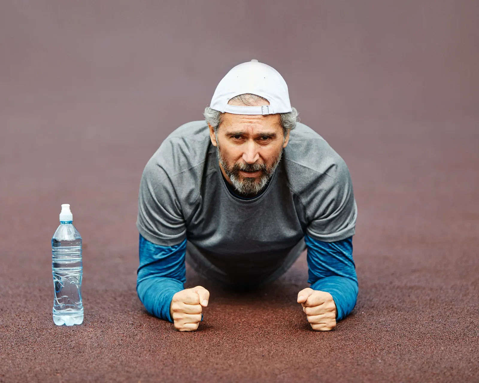 Senior man in a plank position in the gym, a strength move for visible abs over 40
