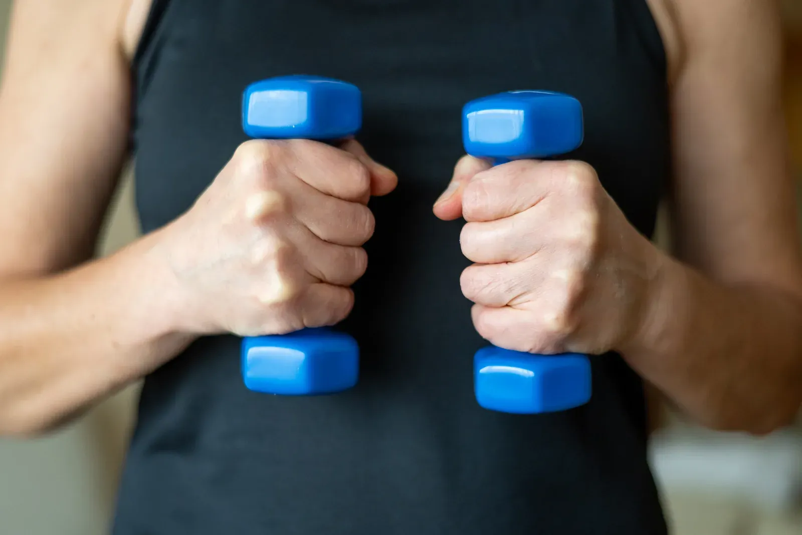 Mature woman over 50 lifting hand weights during a home fitness routine, protecting muscle during GLP-1 use