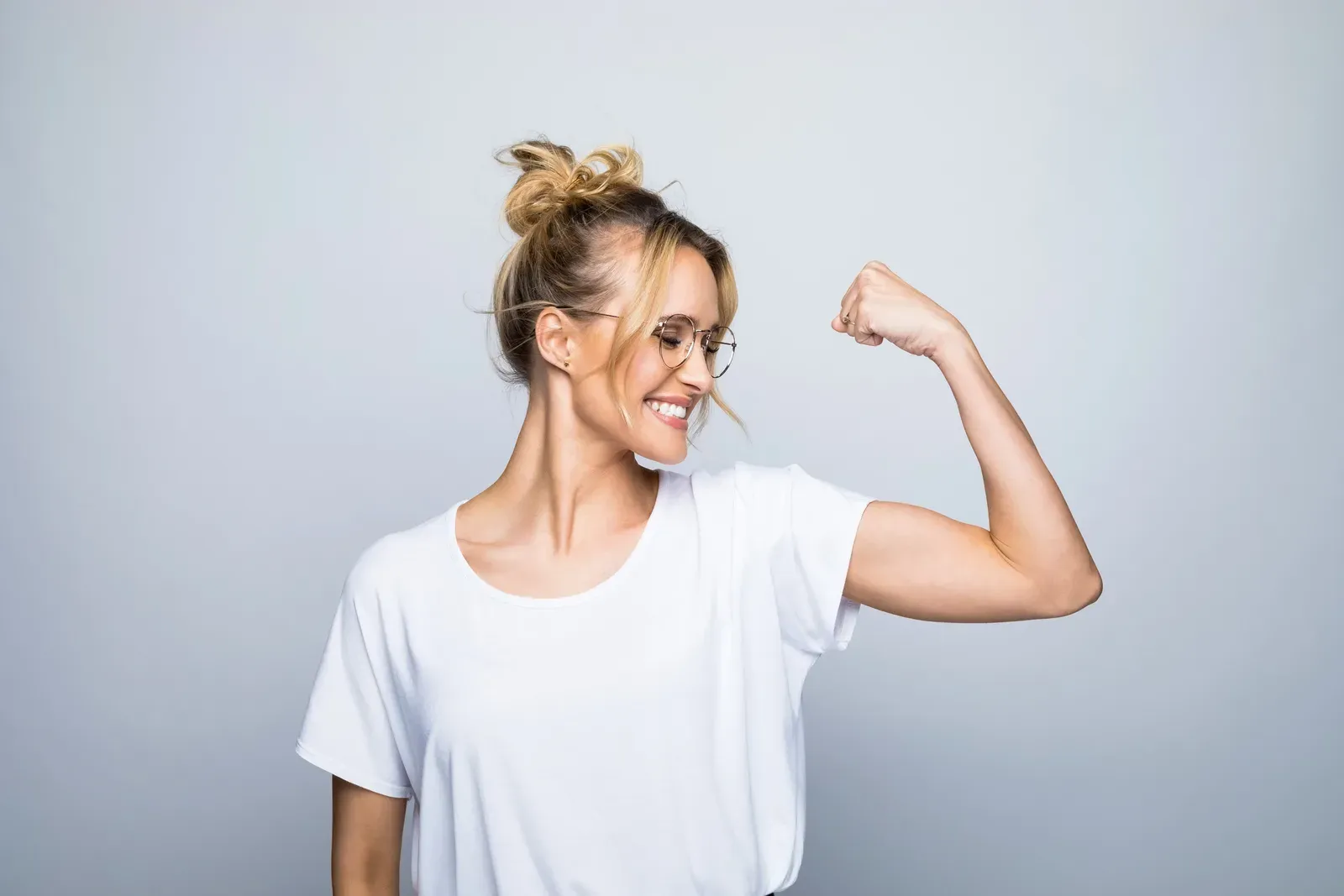 Smiling woman flexing her arm muscles with a confident pose