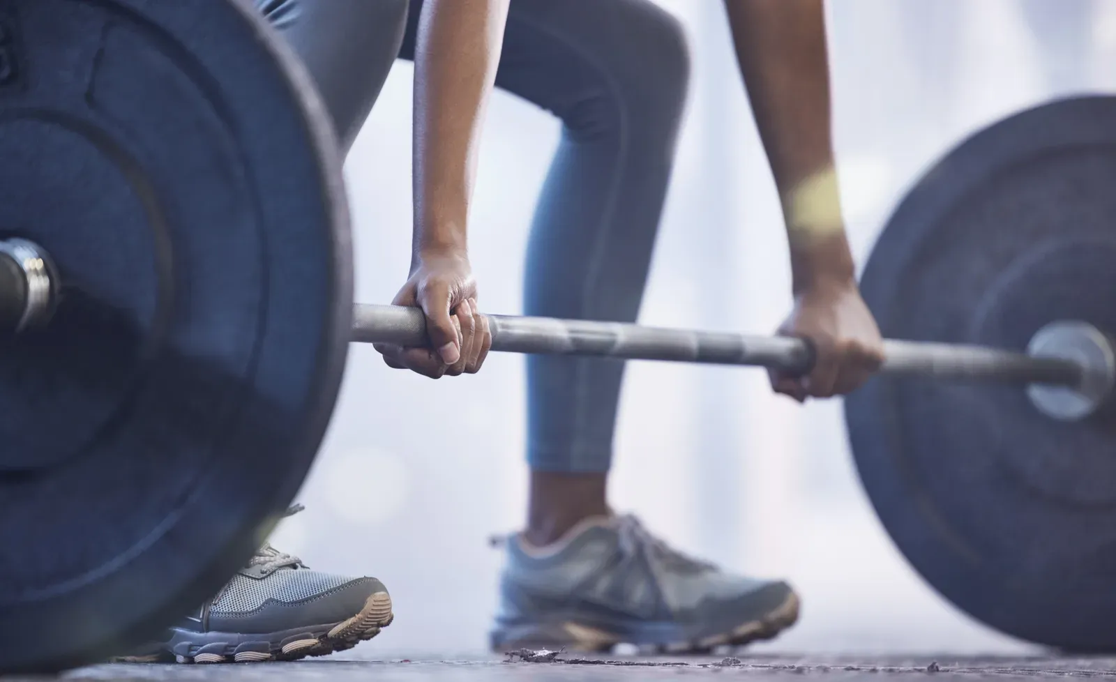 Close view of a woman's hands gripping a barbell during a workout