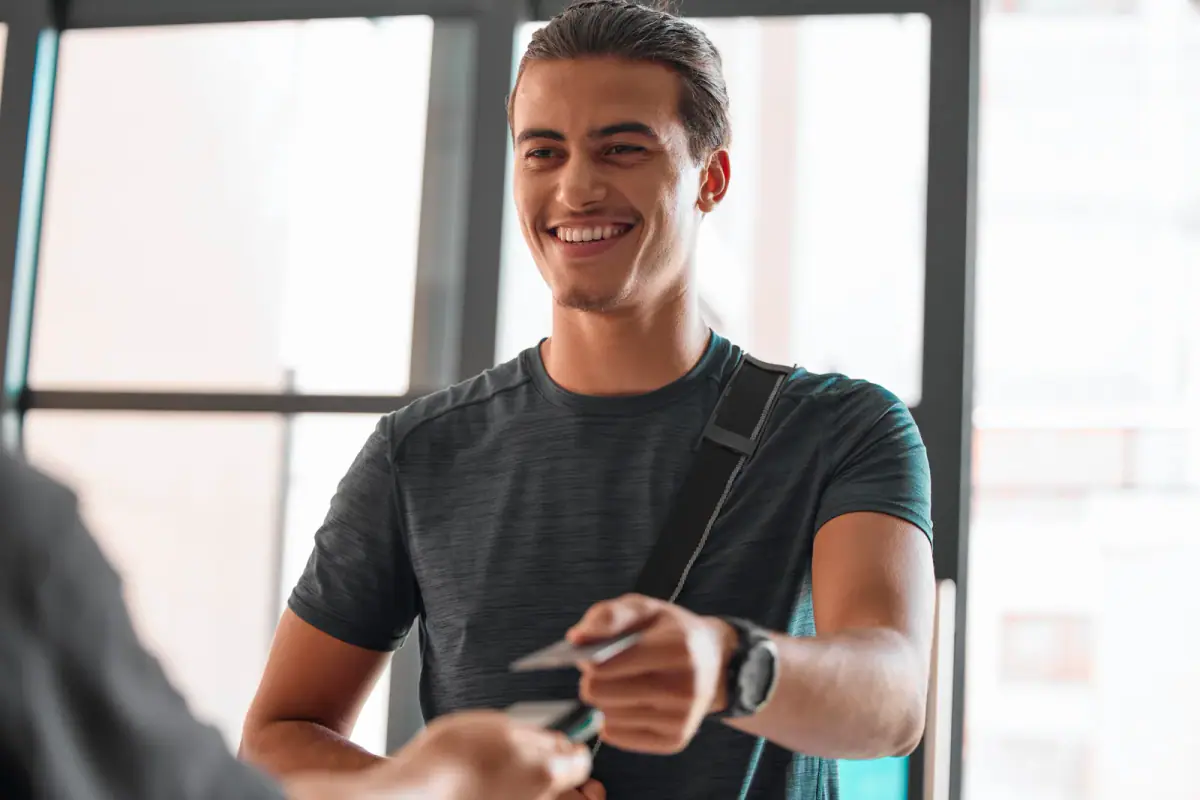 Person weighing workout options while standing with a gym bag in a bright hallway