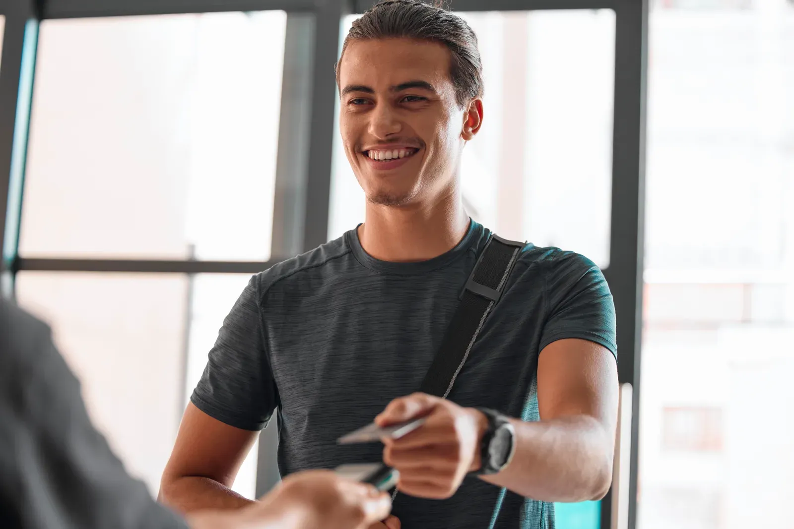Person weighing workout options while standing with a gym bag in a bright hallway