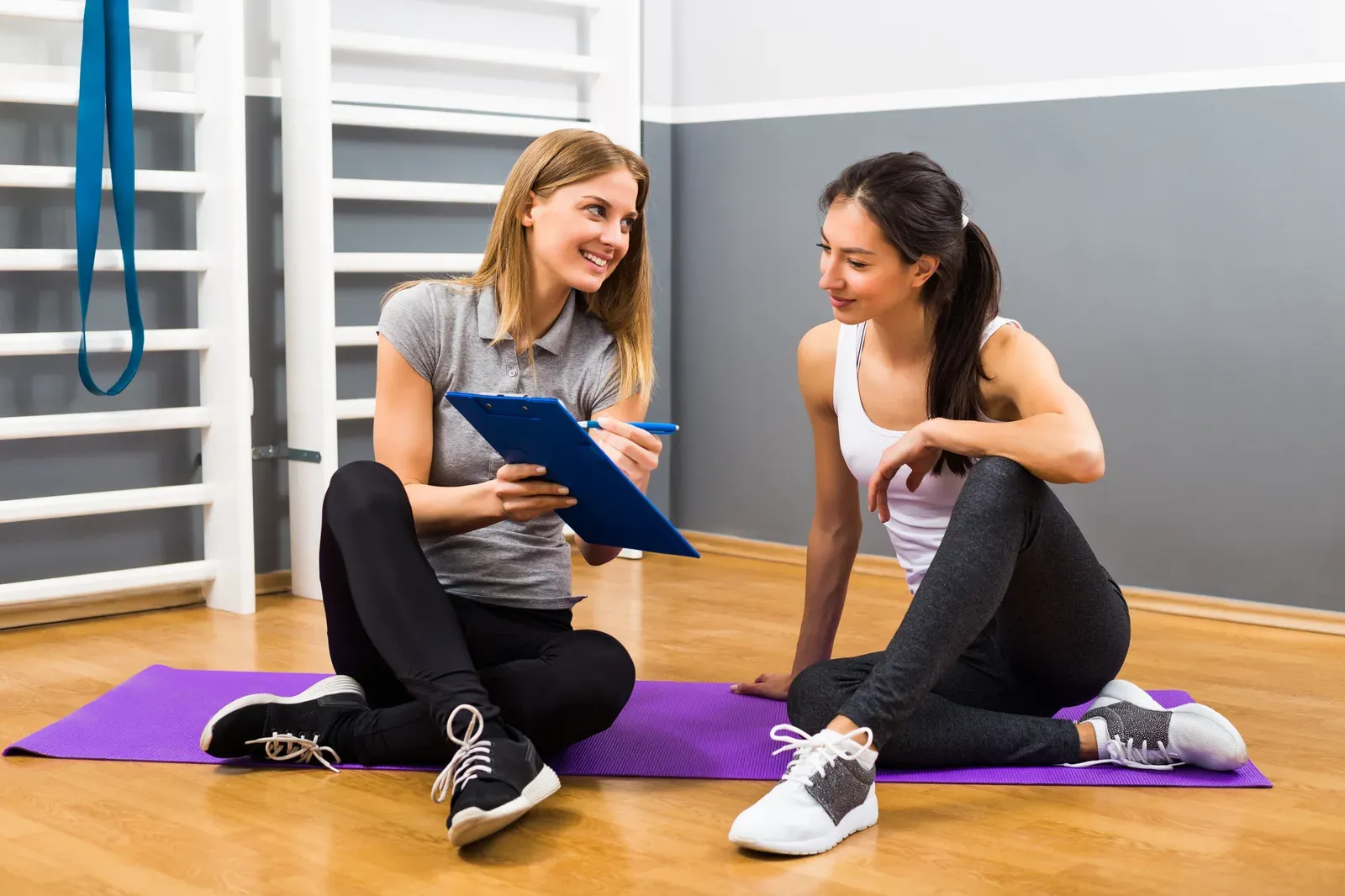 Woman talking with her personal trainer, a conversation that helps clarify a health coach versus a trainer
