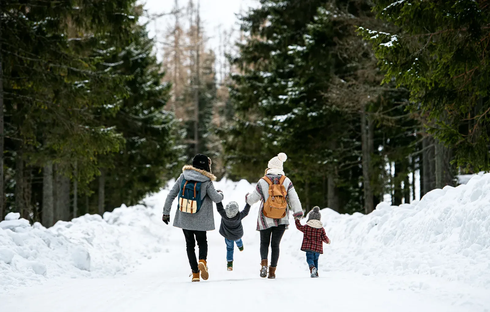 Family with two small children walking through snow, staying active over the holidays