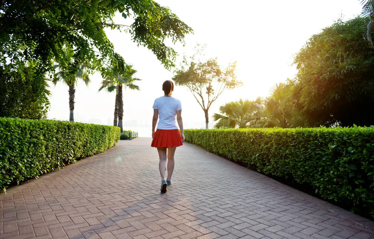 Woman walking along a brick footpath, an easy first step toward fitness