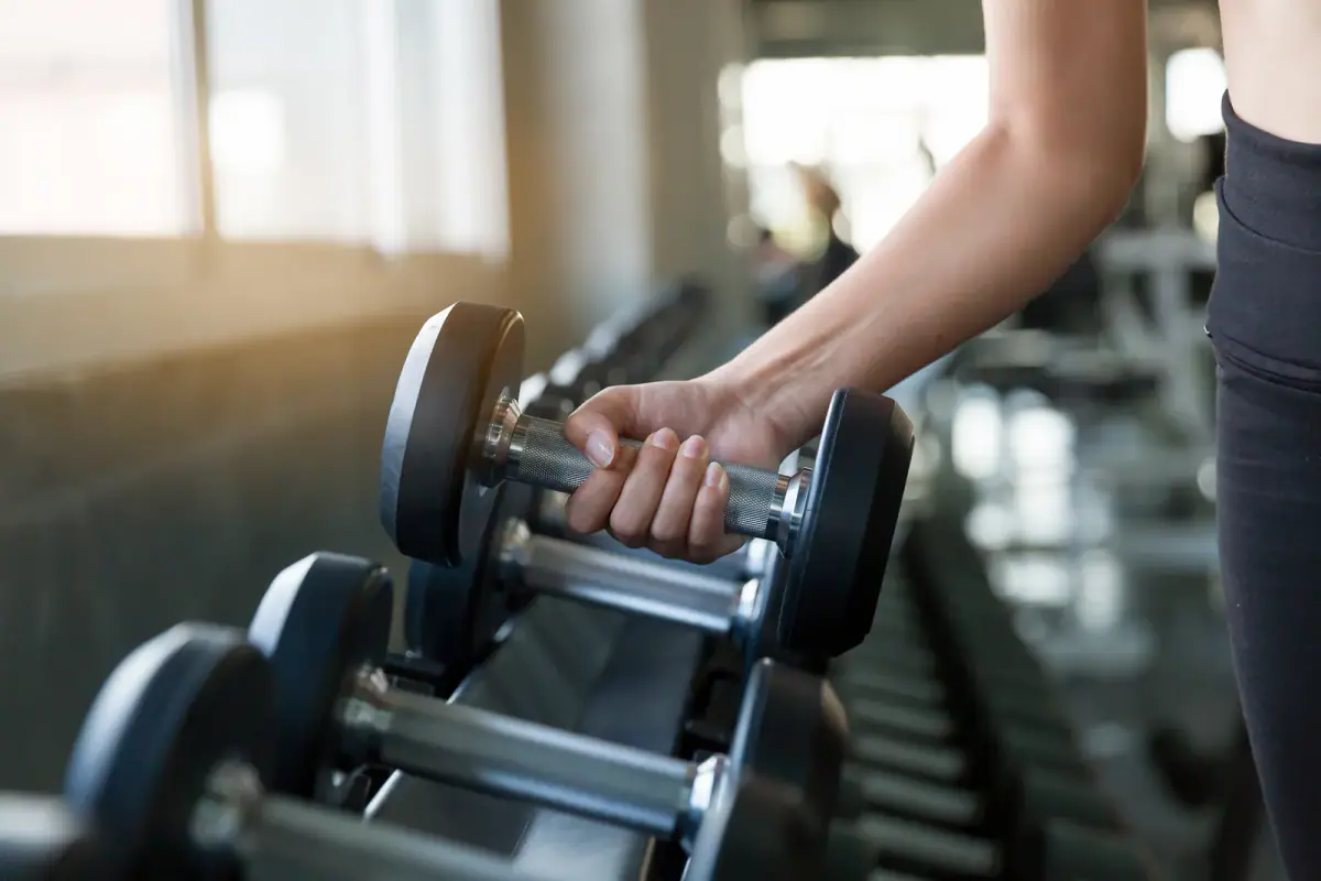 Reaching for a dumbbell on the rack, building strength that keeps weight off