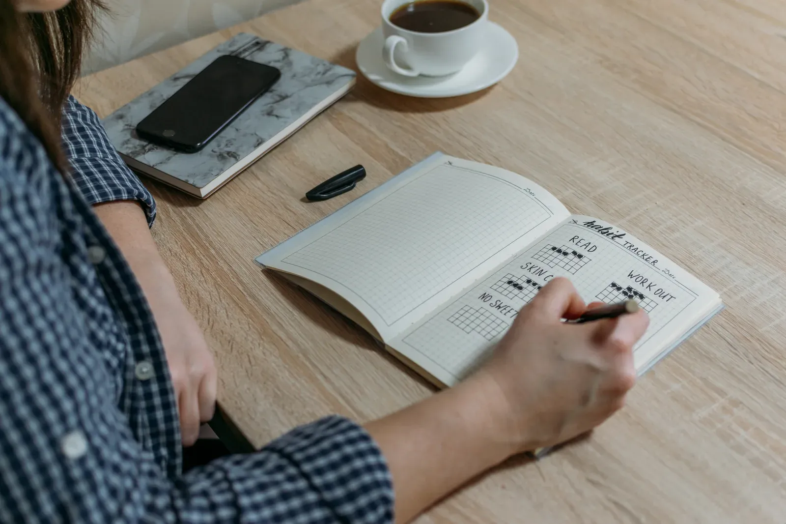 Crossing off another day in a habit tracker journal while building an exercise routine