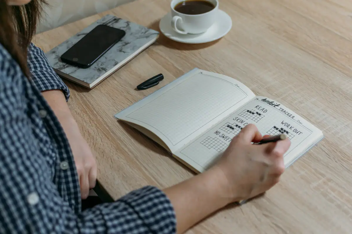 Crossing off another day in a habit tracker journal while building an exercise routine
