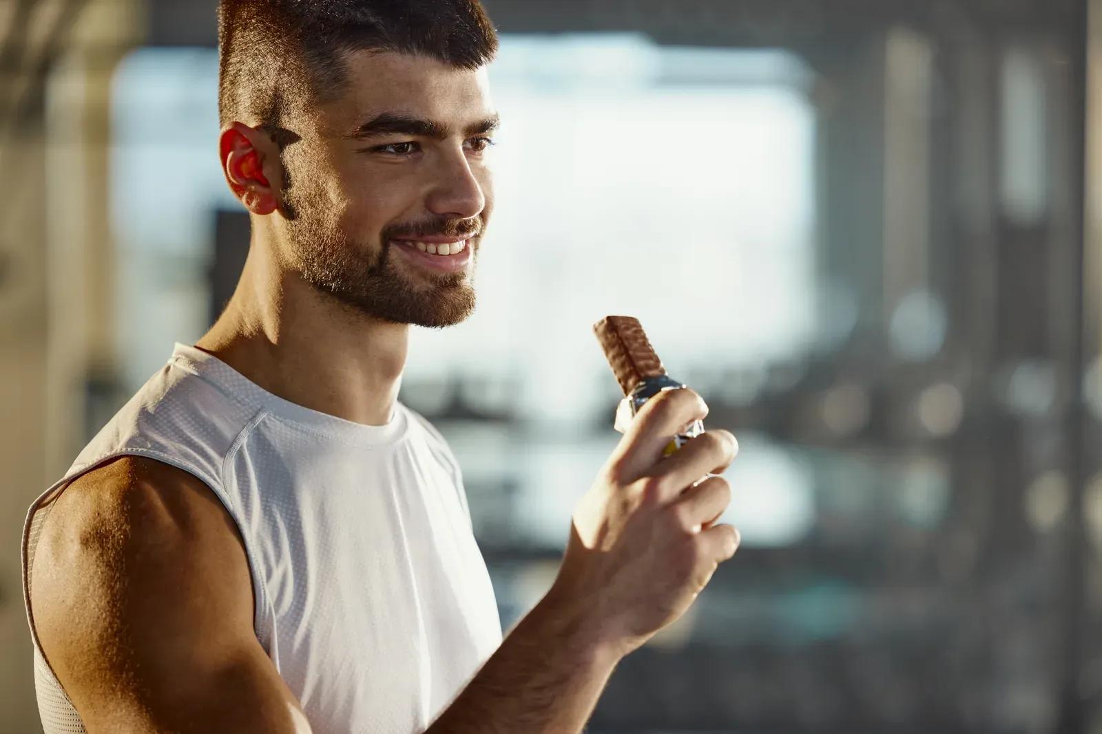 Happy sportsman eating protein in a gym, one part of eating enough to build muscle