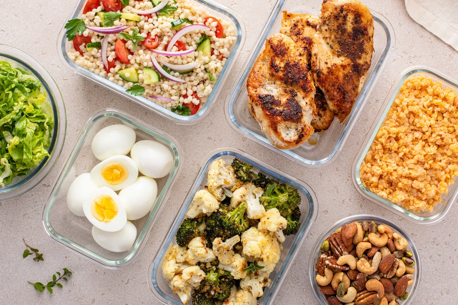 Healthy meal prep with cooked chicken breast, boiled eggs, roasted vegetables and lentils