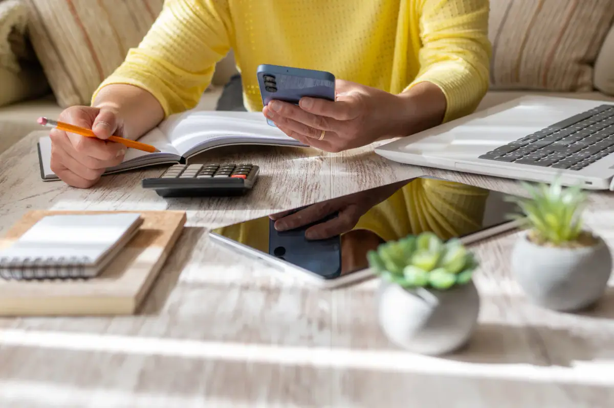 Comparing coaching quotes at a coffee table with laptop and calculator