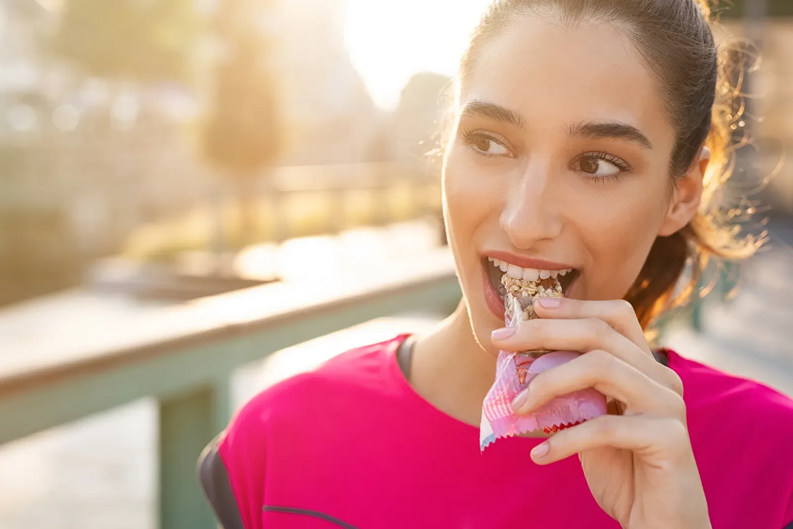 Sporty woman eating an energy bar, one reason appetite may change after starting to lift