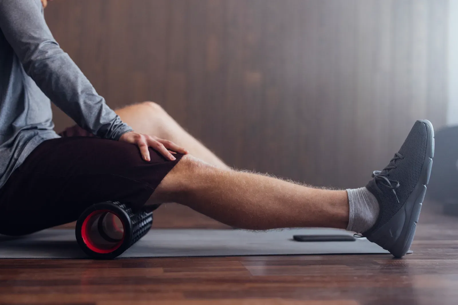 Fit man using a roller for a massage to warm up before a workout, a step to ease joint pain when lifting