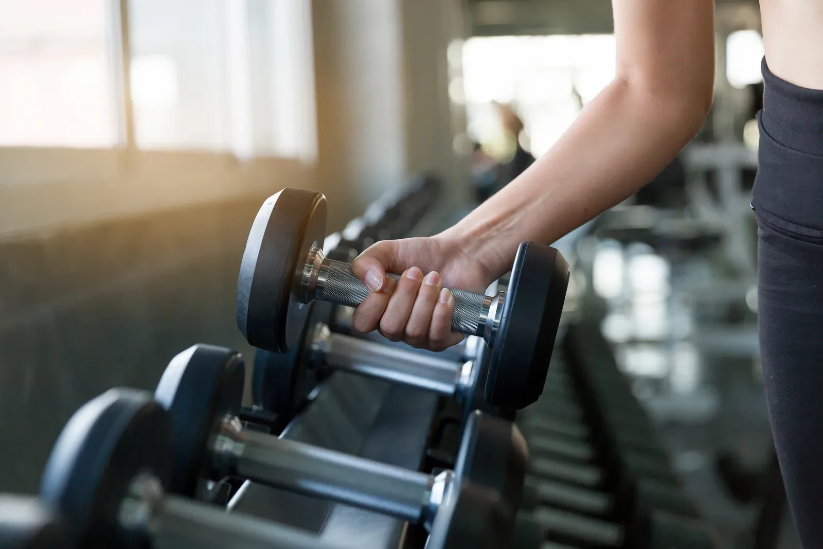Reaching for a dumbbell on the rack, building strength that keeps weight off