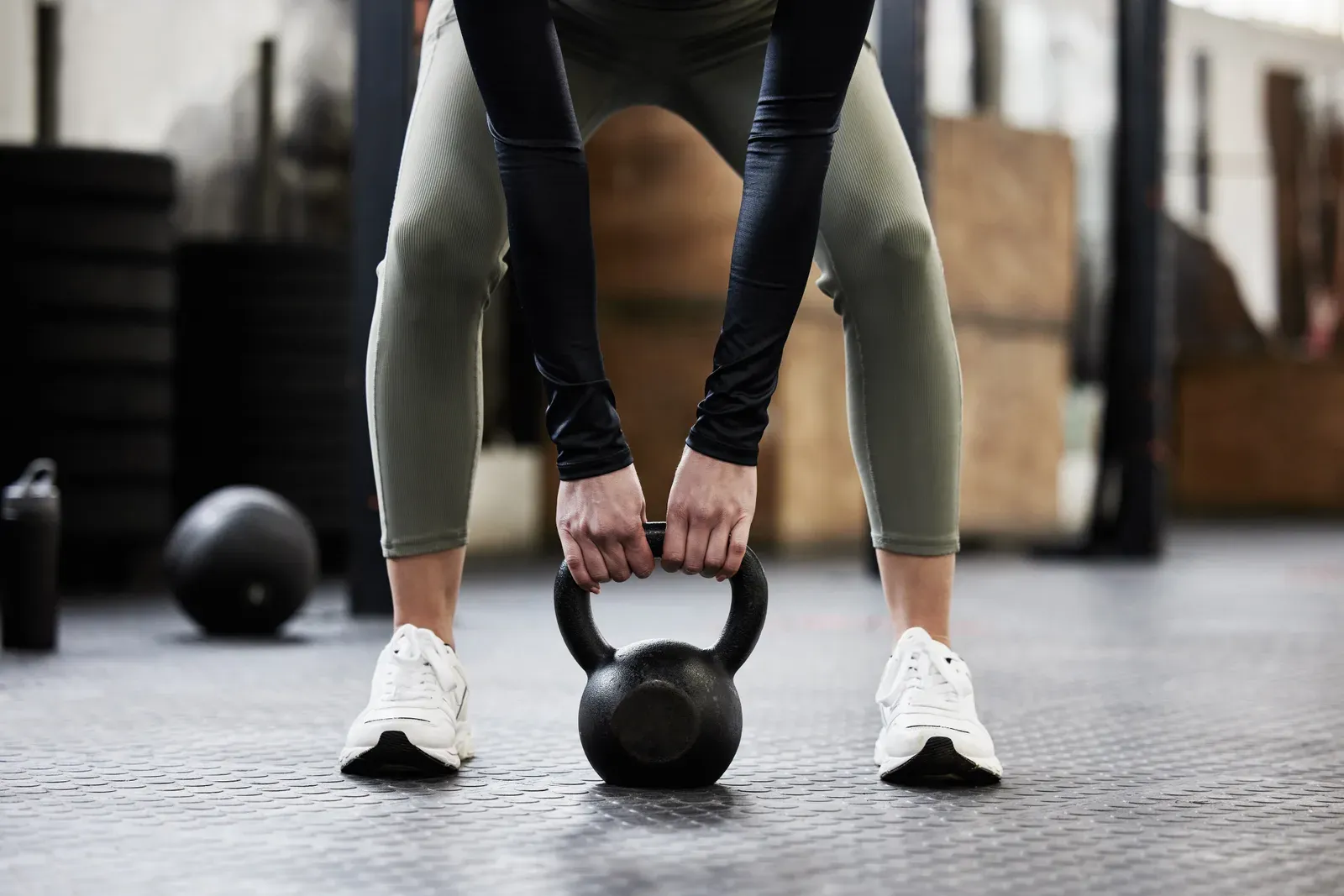 Athlete performing a kettlebell swing under a coach's supervision in a training studio