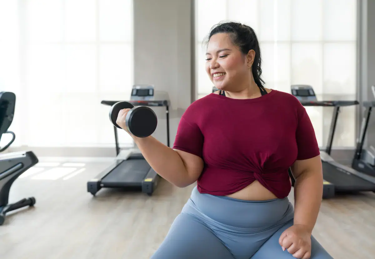 A plus size woman training with resistance bands alongside an encouraging coach in a private studio