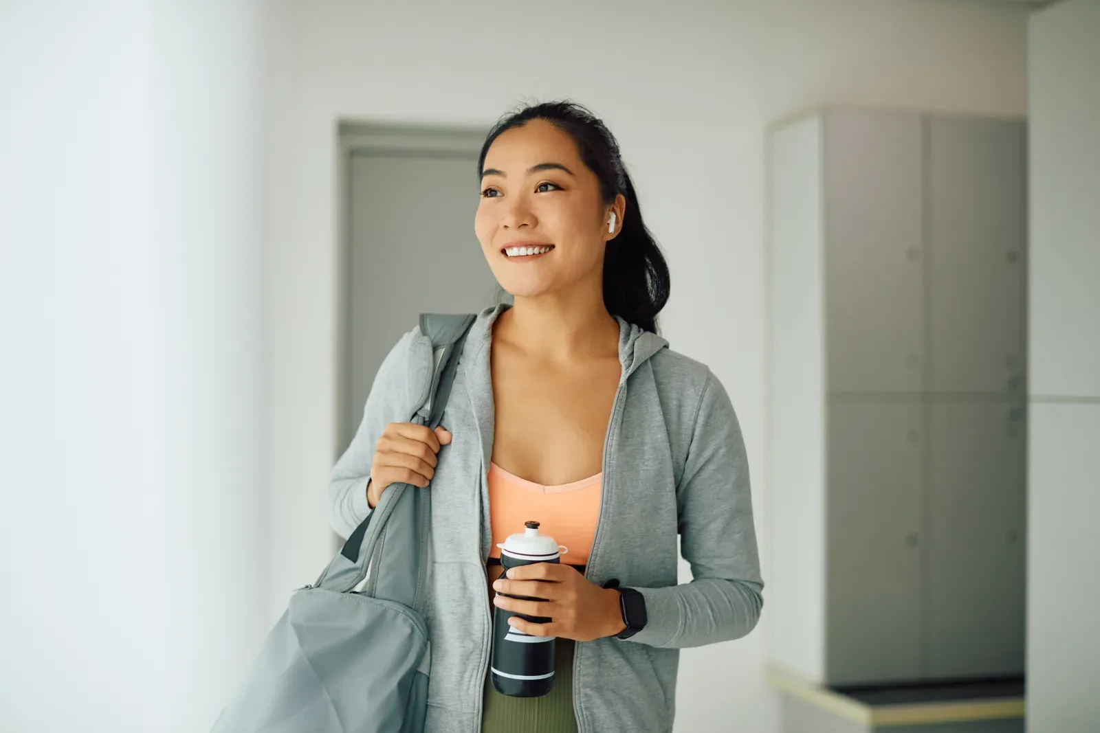 Happy woman arriving at a health club to practice, a quick workout that fits a lunch break