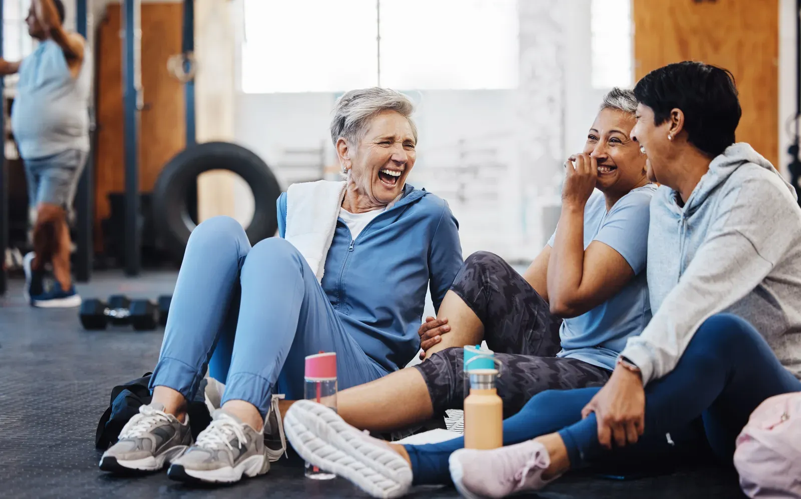 Mature women laughing and chatting after a fitness class, social movement at midlife