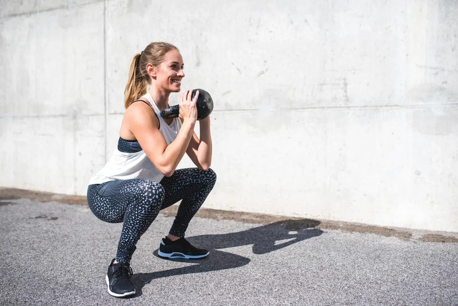A midlife woman training with a kettlebell in a bright studio