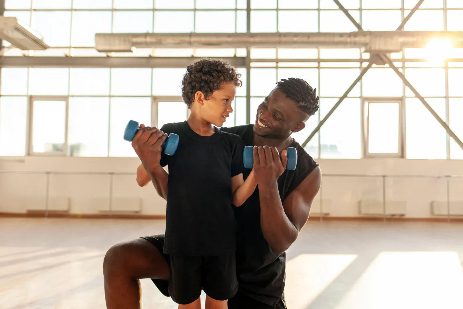 Young teen practicing a goblet squat with light weight while a coach watches form closely