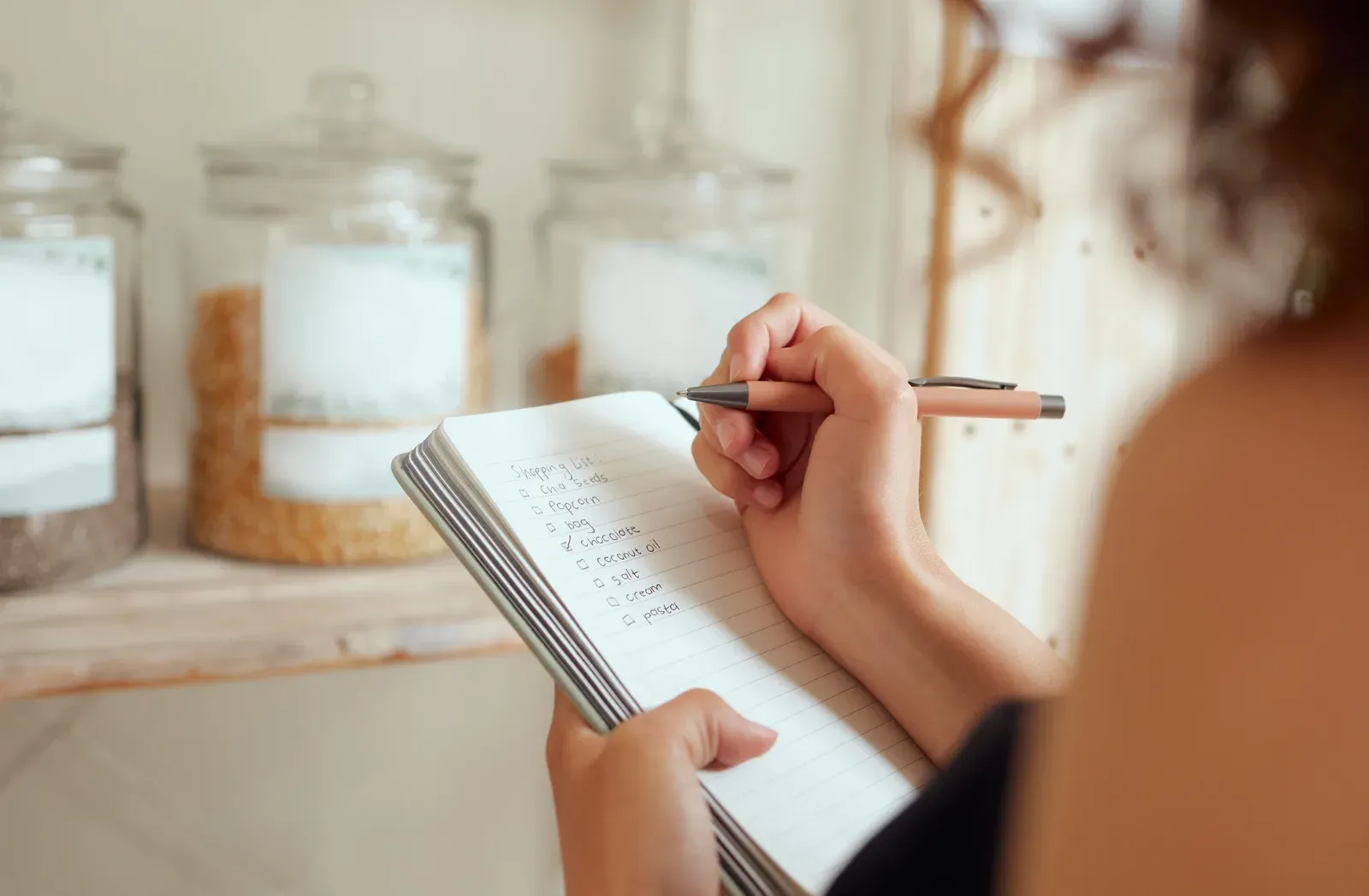 Weekly meal plan being written out in a notebook beside fresh ingredients