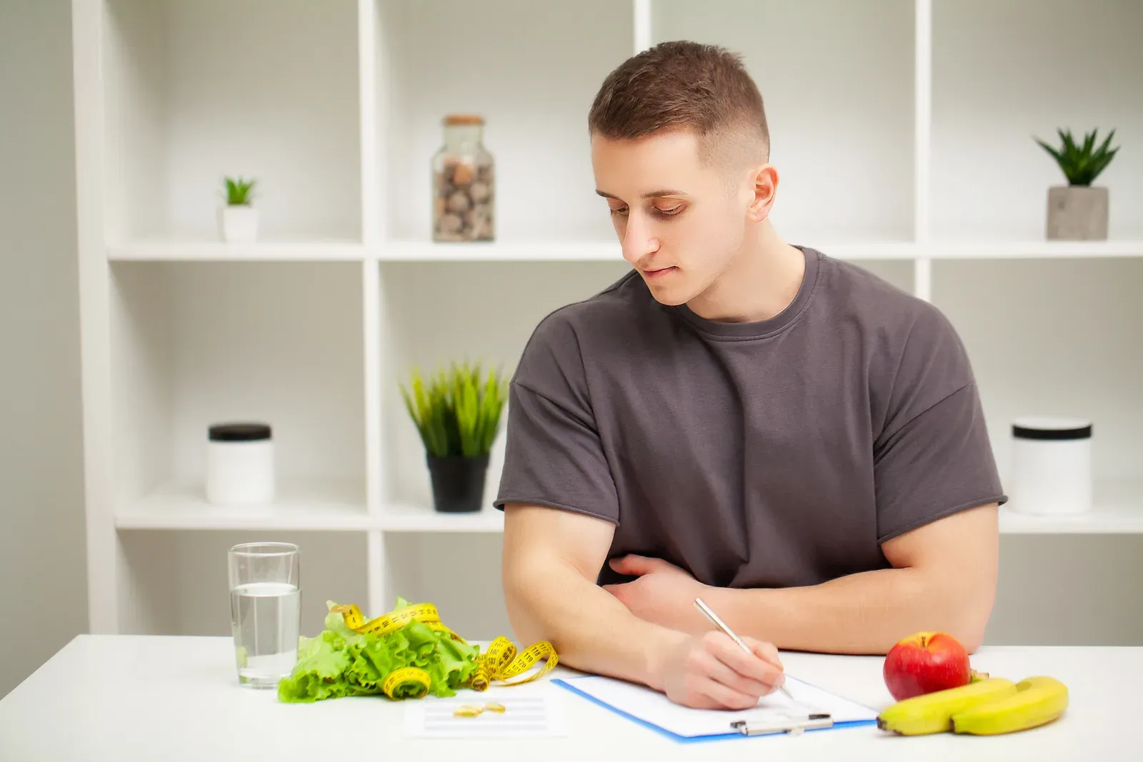 A coach and client reviewing a food journal together at a table with a meal prep container