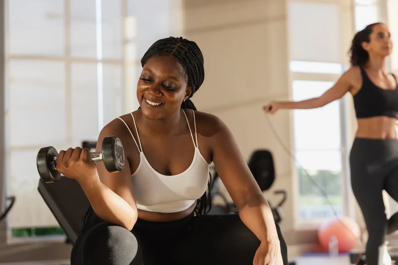 Woman lifting light dumbbells with focused form in a quiet, private training room