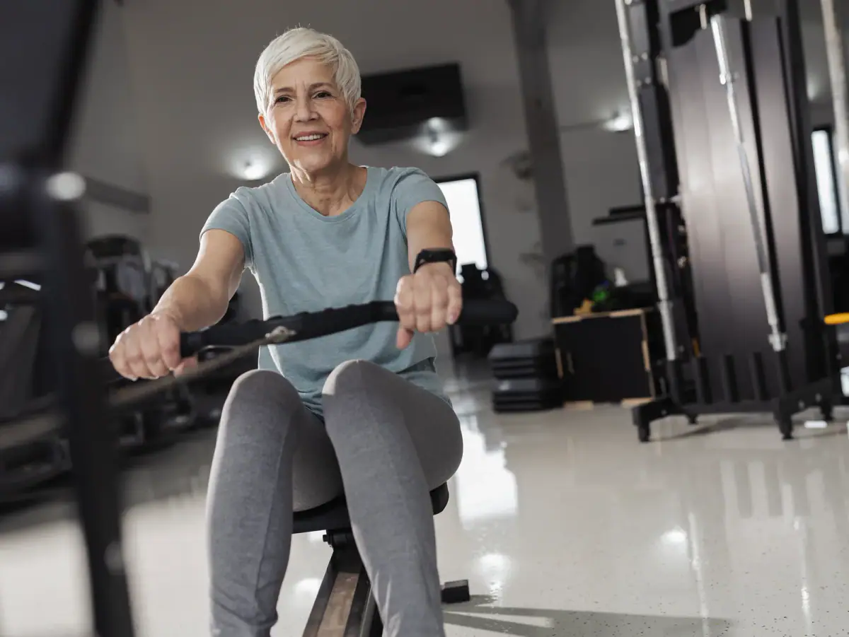 Older man walking at an easy pace on a treadmill in a bright, quiet training room