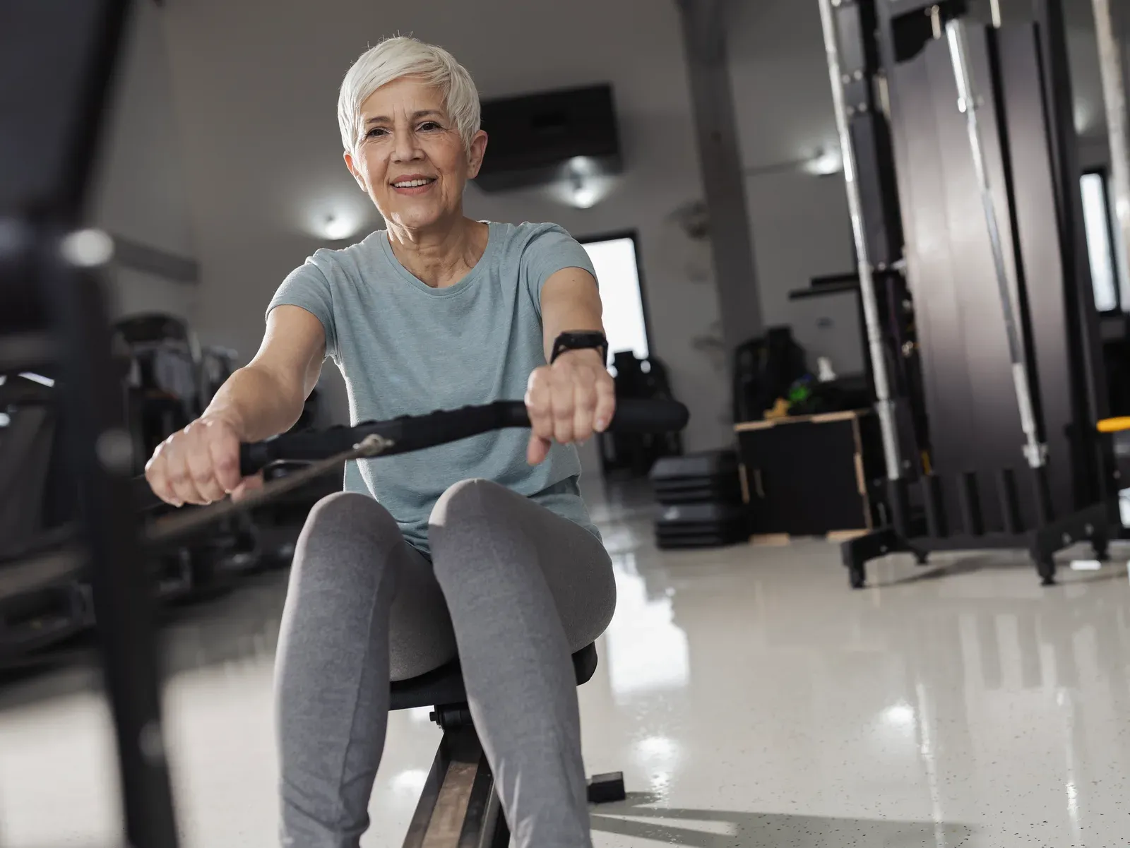 Older man walking at an easy pace on a treadmill in a bright, quiet training room