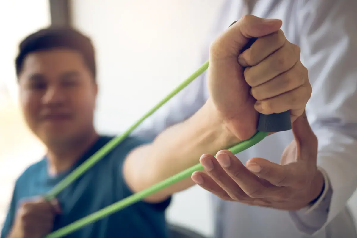 Woman performing a light resistance band shoulder exercise in a training room