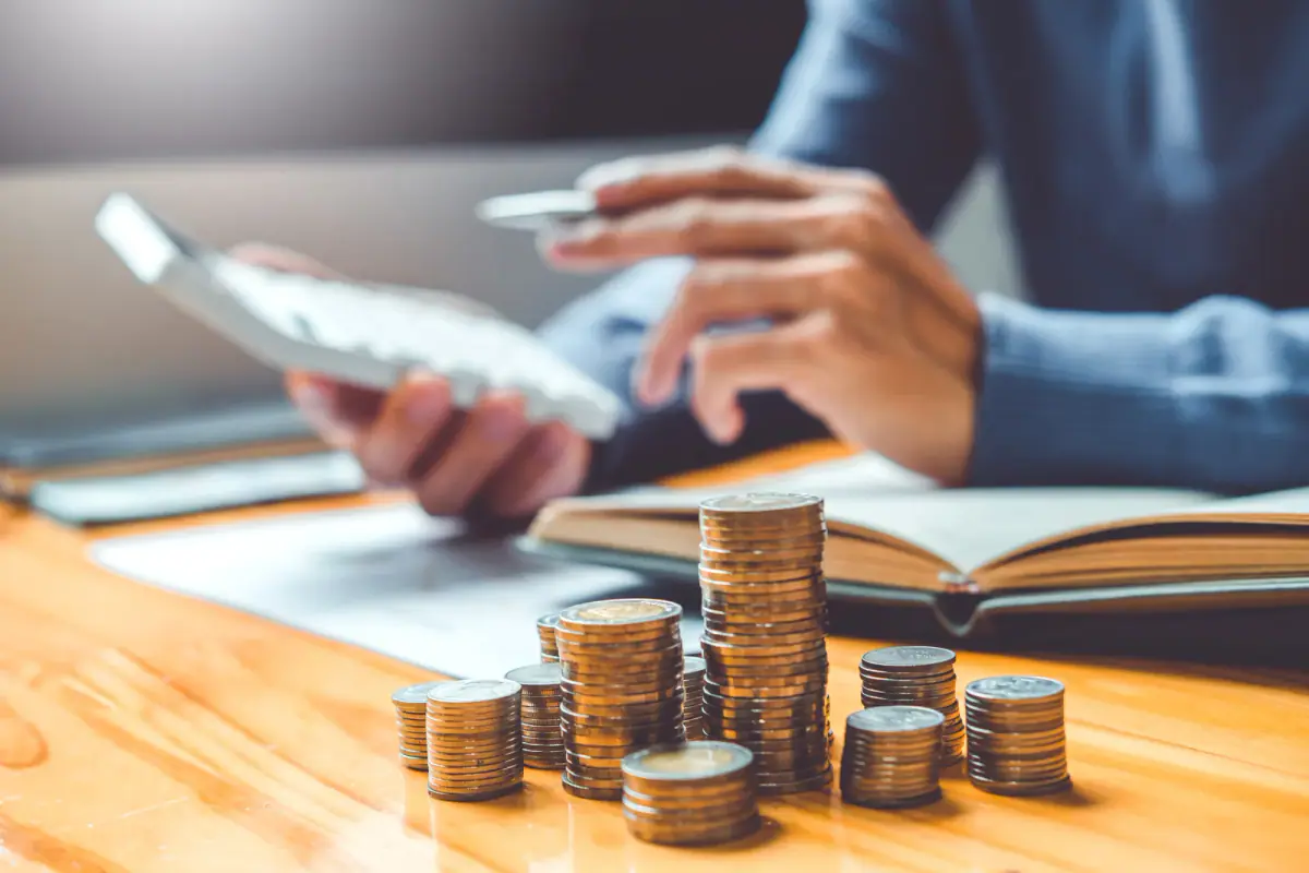 Stacking coins in rows while budgeting for monthly personal training costs