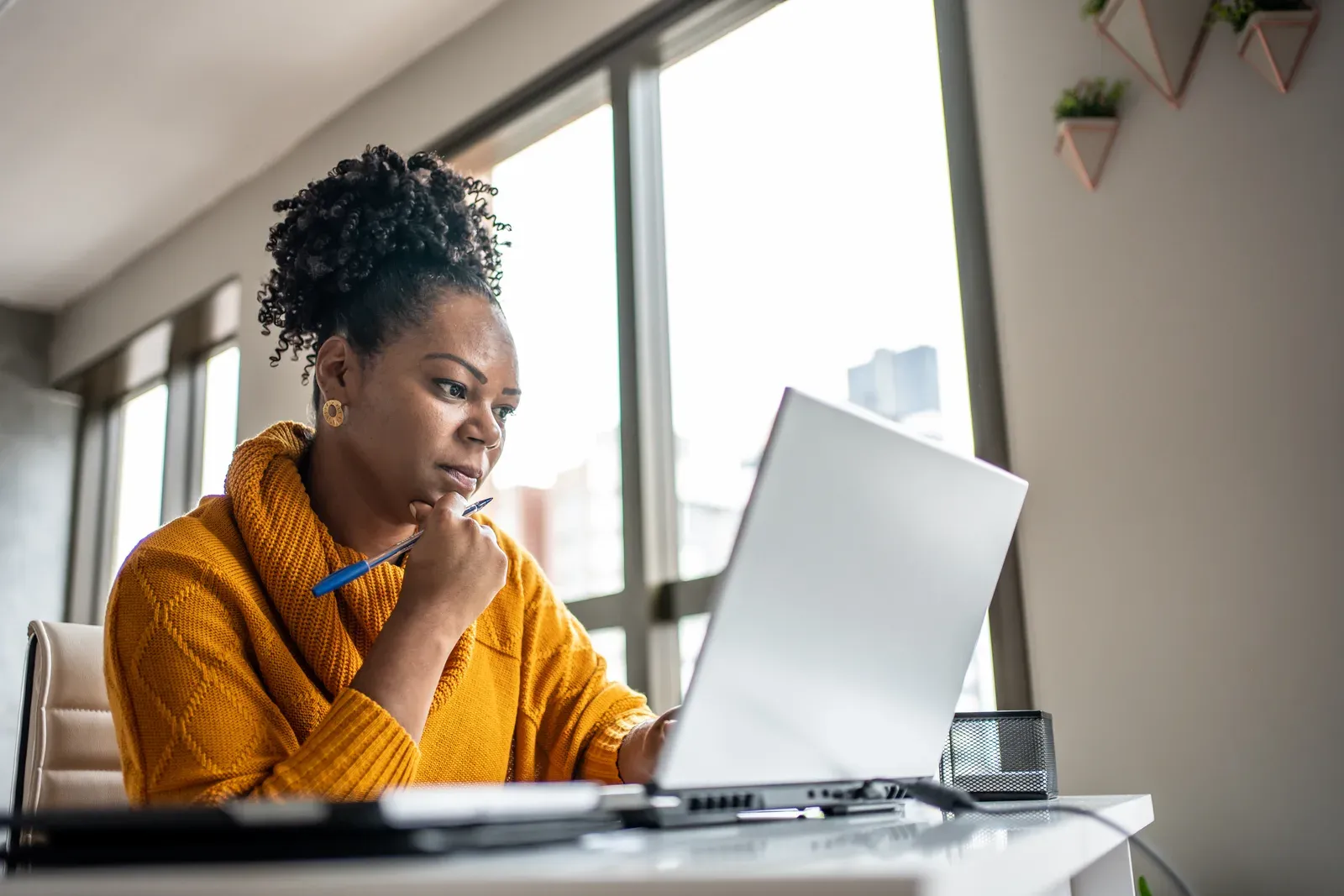 Remote worker closing a laptop at a home desk with a packed gym bag waiting by the door
