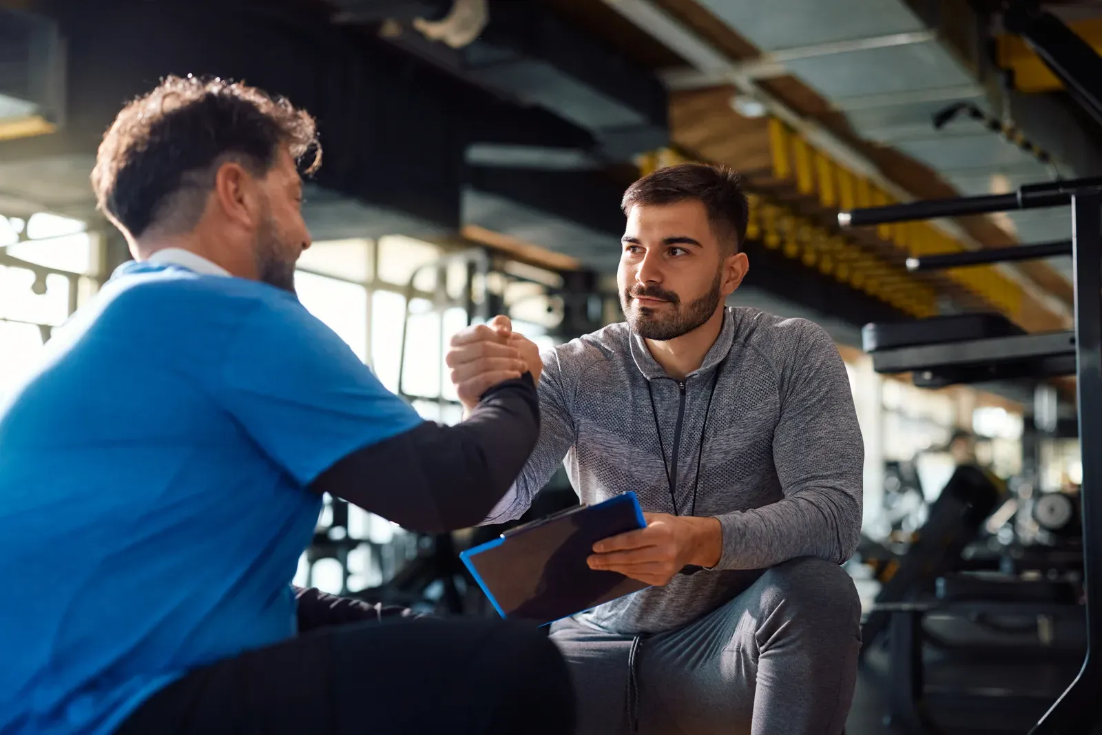 Coach shaking hands with a new client at the start of a gym consultation