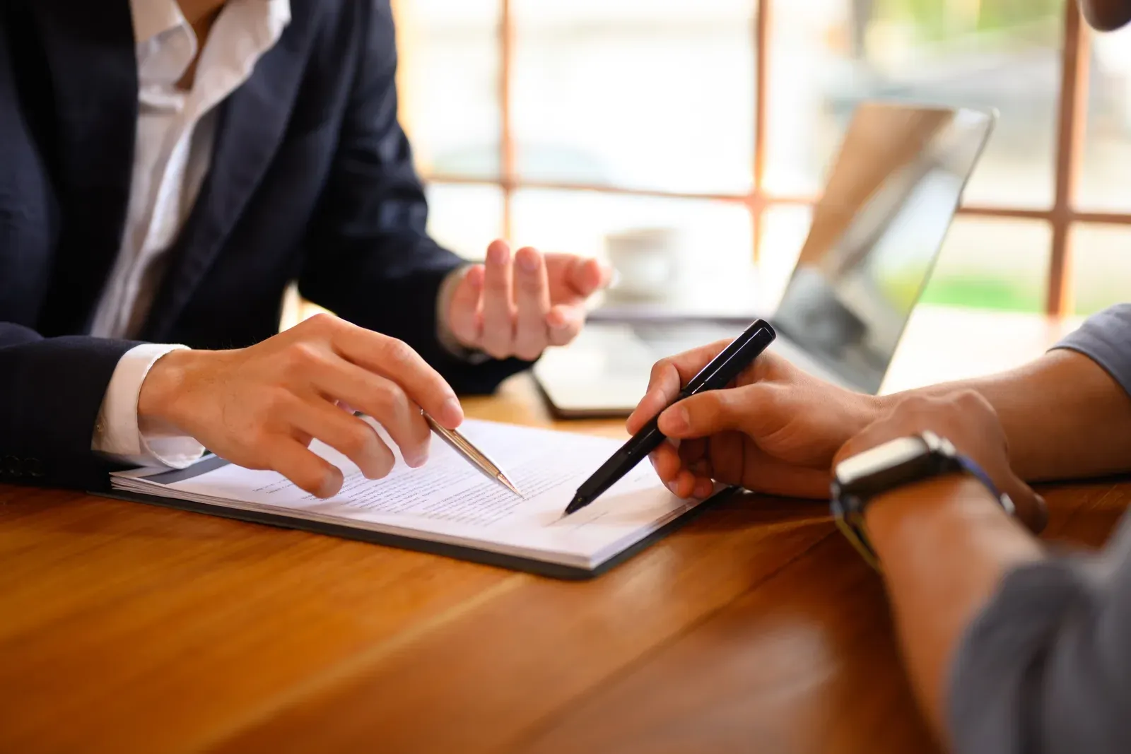 Lawyer or insurance agent pointing at a contract and showing a male client where to sign