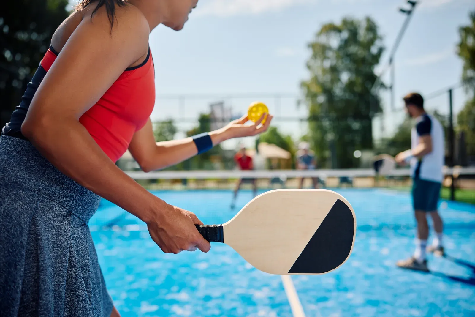 Two pickleball players reaching for a low volley at the net during a doubles rally