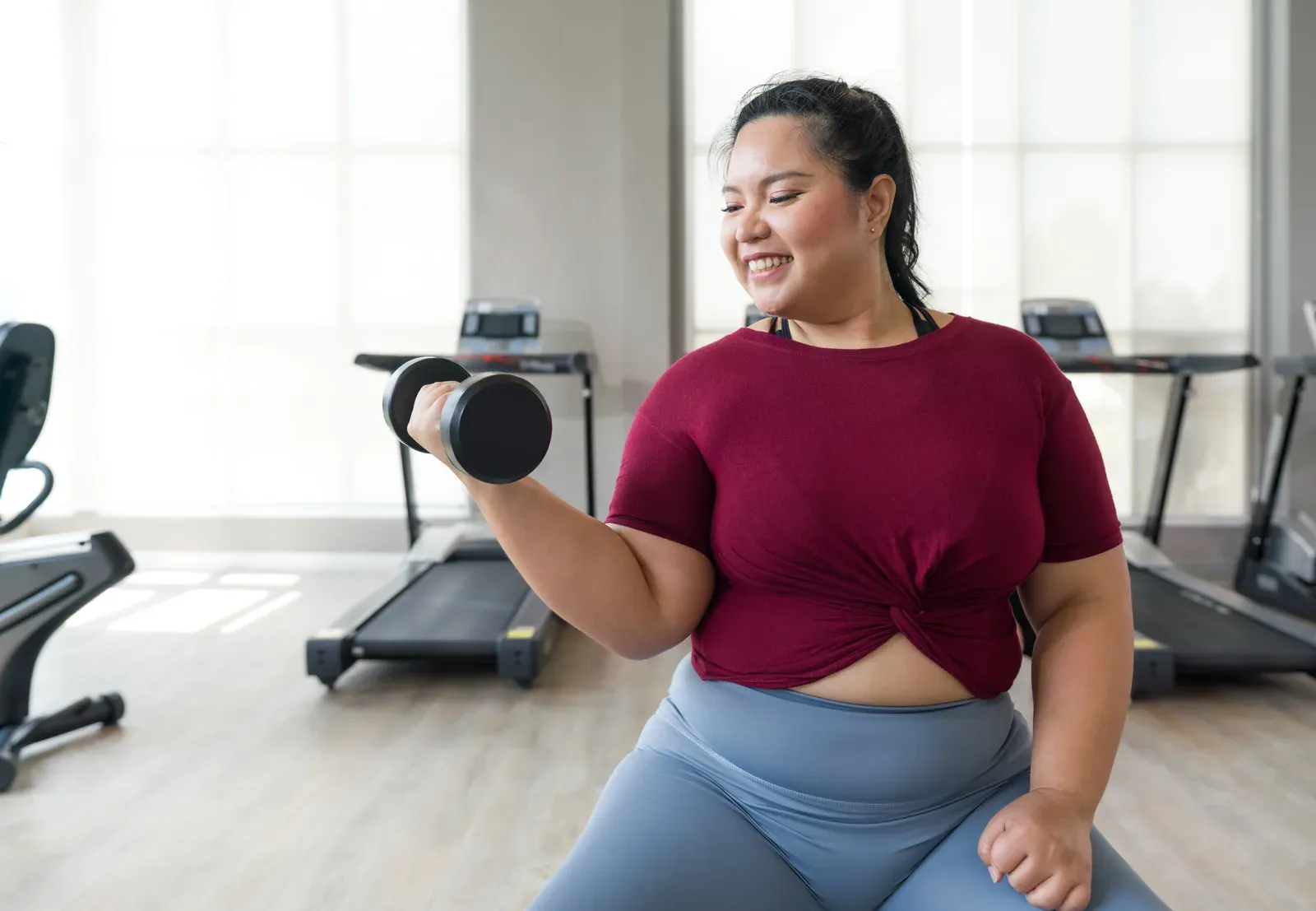 A plus size woman training with resistance bands alongside an encouraging coach in a private studio