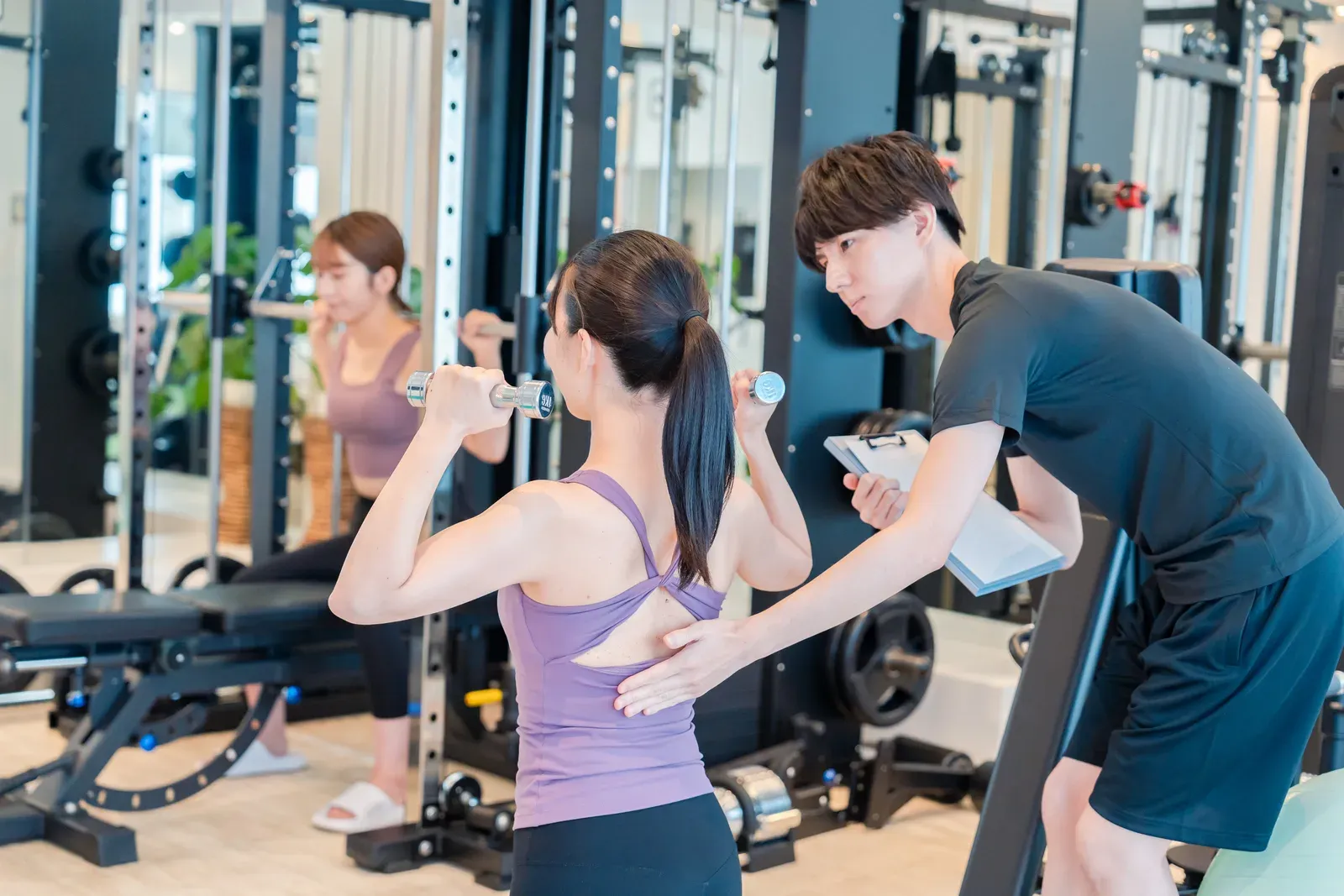 Coach guiding a client through a strength exercise in a small private training room