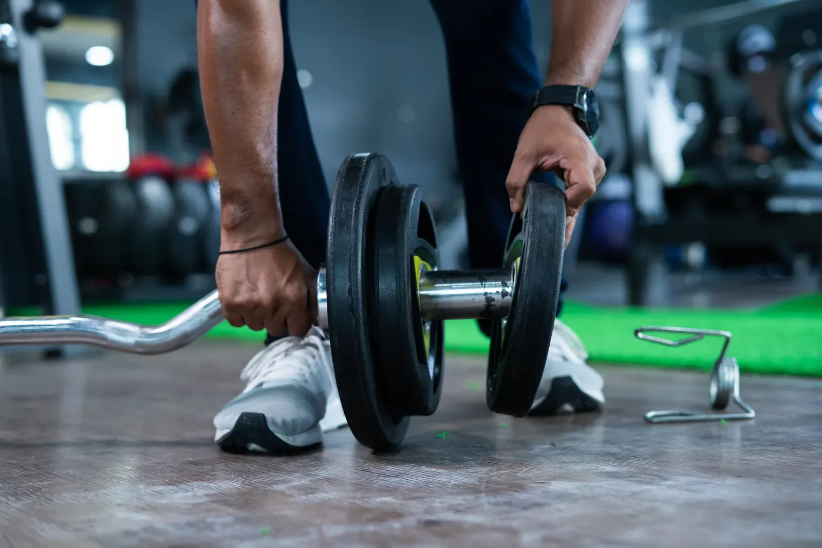 Hands adding a weight plate to a barbell, progressive overload in action